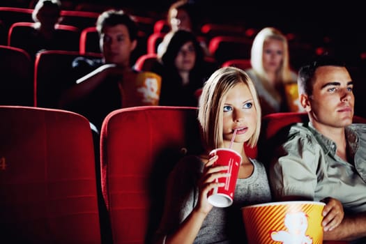 Seat, popcorn and a couple in the cinema watching a movie for entertainment while on a date. Love, food or romance and young people in a theater audience to experience a film together with a drink.