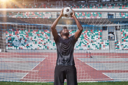 african american football player holding the ball in his hands at the stadium