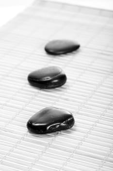 Three Zen stones on bamboo mat,black