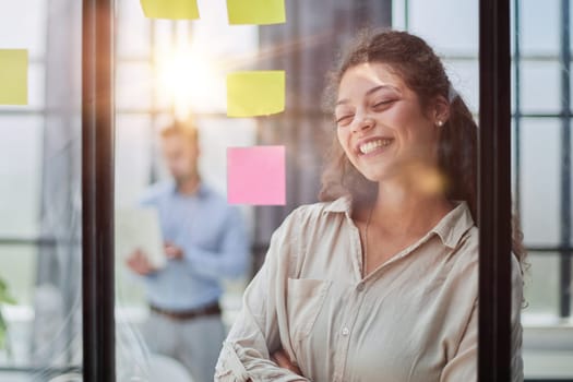 Bringing her vision to life. Shot of a confident businesswoman presenting an idea to her colleague using adhesive notes on a glass wall in the office.