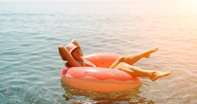 Summer vacation woman in hat floats on an inflatable donut mattress. Happy woman relaxing and enjoying family summer travel holidays travel on the sea