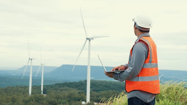 Engineer working on a wind farm atop a hill or mountain in the rural. Progressive ideal for the future production of renewable, sustainable energy. Energy generation from wind turbine.