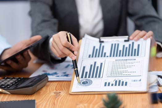 Multiracial analyst team use BI dashboard data to analyze financial report on meeting table. Group of diverse business people utilize data analysis by FIntech for business marketing decision. Concord