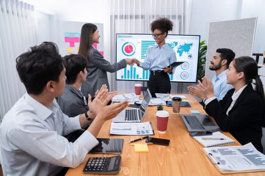 Diverse coworker celebrate with handshake and teamwork in corporate workplace. Happy business people united by handshaking after successful meeting or business presentation on data analysis. Concord