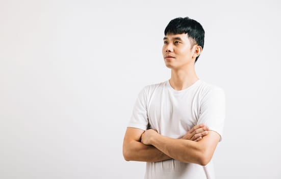 Portrait of a confident young Thai man with crossed arms, exuding success and a cheerful smile. Studio shot isolated on white background, radiating positivity.