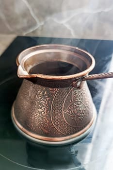 steaming coffee in a cezve on the kitchen stove.