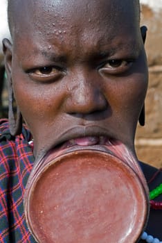 Woman of the Mursi tribe with the typical clay lip plates,southern Ethiopia,near the Sudanese border. There are several theories for the cause of this custom. One of them is that the mutilation of the young girls for the slaves