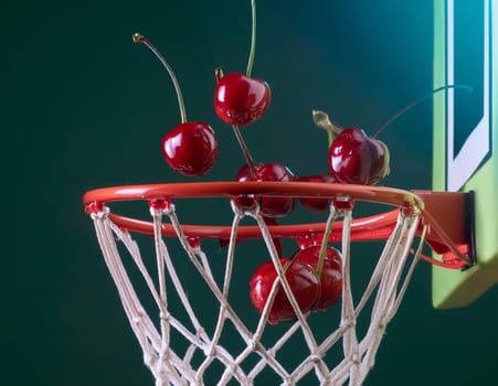 Cherries scoring in mini basketball hoop against green background.