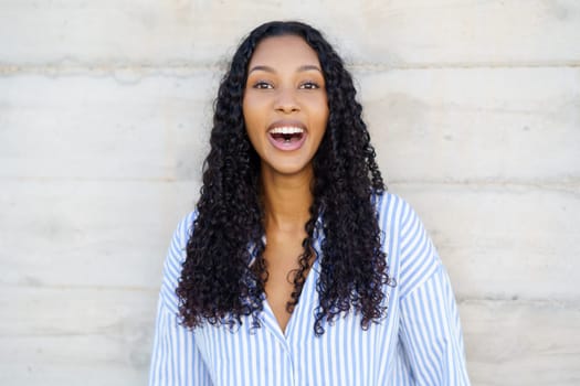 A cheerful young woman with curly hair radiates joy and positivity, leaving a delightful and uplifting atmosphere that is perfectly suited for various lifestyle and wellness themes and topics