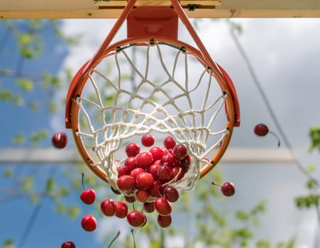 Red cherries scoring through a basketball hoop against blue sky.