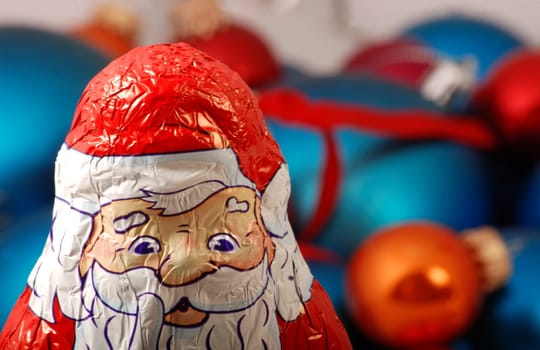 Chocolate Santa Claus in front of Christmas baubles