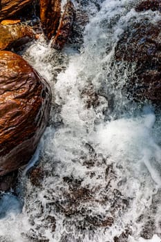 River water flowing between rocks with bubbles and foam