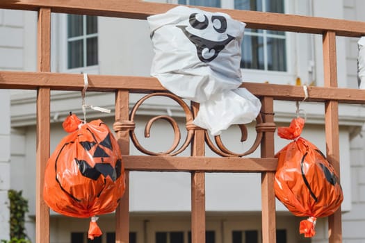 Artificial pumpkin heads from a plastic bag on the fence House in background.