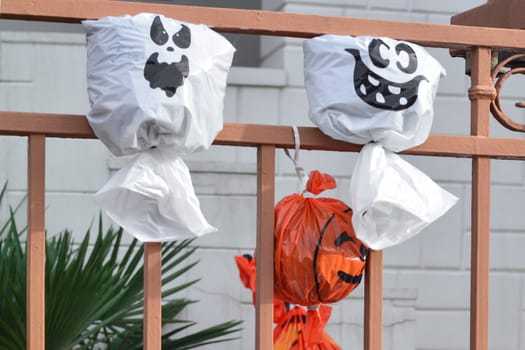 Artificial pumpkin heads from a plastic bag on the fence House in background.