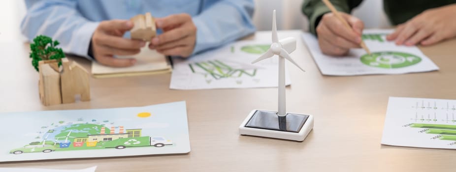 Business people invest in green business plan at meeting room on table with house model and wind mill placed represented eco house and renewable energy. Closeup. Delineation.