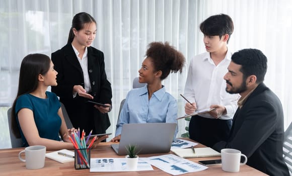 Multiracial analyst team use BI dashboard data to analyze financial report on meeting table. Group of diverse business people utilize data analysis by FIntech for success business marketing. Concord