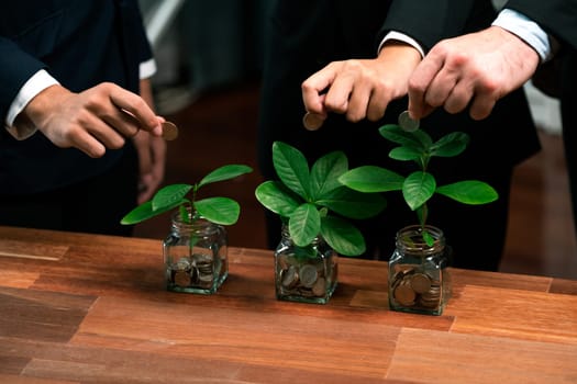 Business people put money saving into jar filled with coins and growing plant for sustainable financial planning for retirement or eco subsidy investment for environment protection. Quaint