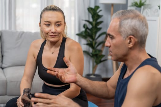 Athletic and sporty senior couple portrait in sportswear sitting on sofa as home exercise concept. Healthy fit body lifestyle after retirement. Clout