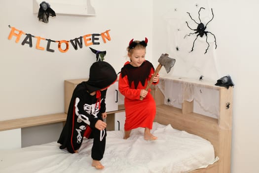 Children in skeleton and witch costume laughing at home halloween
