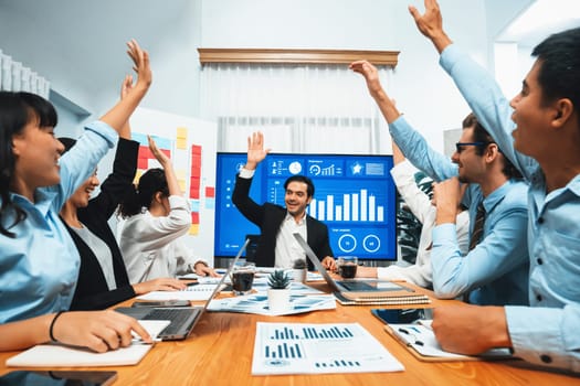 Group of happy multi ethnic businesspeople in celebratory gesture and successful teamwork after made success sales or positive financial data dashboard display on screen in meeting room. Habiliment