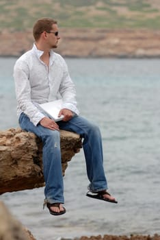 Young man using laptop by the sea
