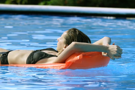 Woman in outdoor pool on air mattress