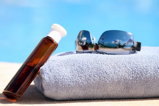 Sunglasses and oil bottle on towel