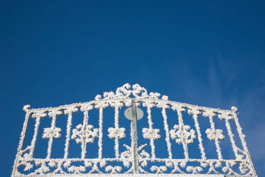 Gate with hoarfrost in front of blue sky