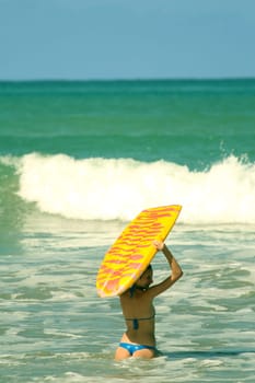 Woman carrying boogie board into water