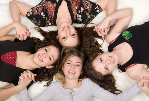 4 teen girls laying on white background