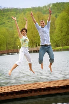 Happy couple jumping at the lake