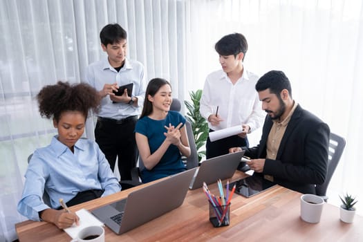 Happy diverse business people work together, discussing in corporate office. Professional and diversity teamwork discuss business plan on desk with laptop. Modern multicultural office worker. Concord