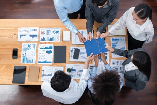 Panorama top view diverse corporate officer worker collaborate in office connect puzzle piece as partnership and teamwork concept. Unity and synergy in business success with jigsaw puzzle. Concord