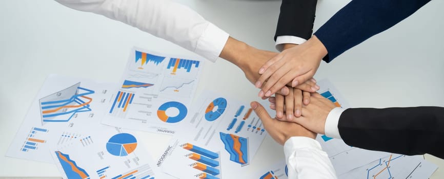 Analyst team putting hand together after successful plan of business strategy and marketing. Teamwork friends and unity cooperation in office with stack hands. Panoramic shot. oratory