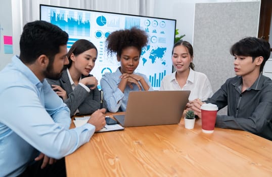 Multiracial analyst team use BI Fintech software to analyze financial data on meeting table. Financial dashboard data display on laptop screen with analyzed chart for marketing indication. Concord