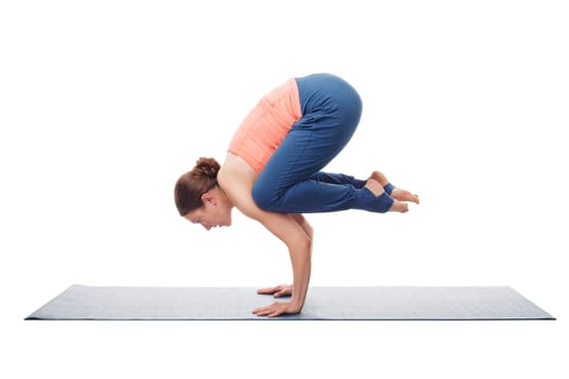 Beautiful sporty fit yogini woman practices yoga asana Bakasana - crane pose arm balance isolated on white