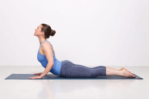 Beautiful sporty fit yogini woman practices yoga asana bhujangasana - cobra pose in studio