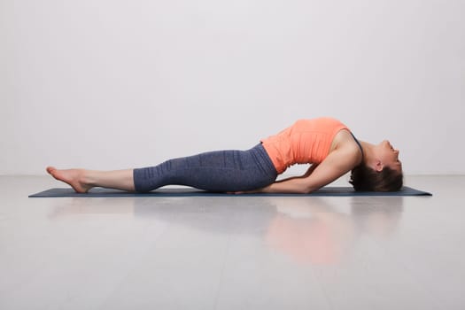 Beautiful sporty fit yogini woman practices yoga asana Matsyasana - fish pose variation in studio