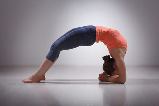 Beautiful sporty fit yogini woman practices yoga asana viparita dandasana - upward facing two feet staff pose in studio