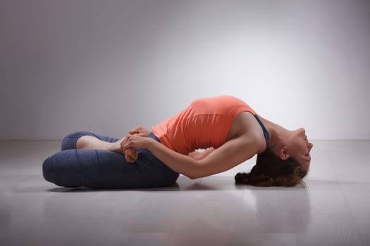 Beautiful sporty fit yogini woman practices yoga asana Matsyasana - fish pose in studio