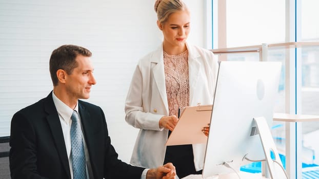 Two business people talk project strategy at office meeting room. Businessman discuss project planning with colleague at modern workplace while having conversation and advice on financial report. Jivy