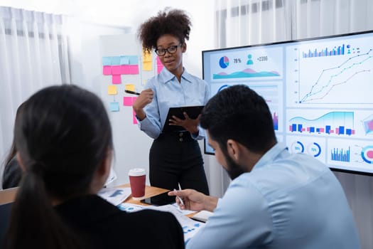 Young african businesswoman presenting data analysis dashboard on TV screen in modern meeting. Business presentation with group of business people in conference room. Concord