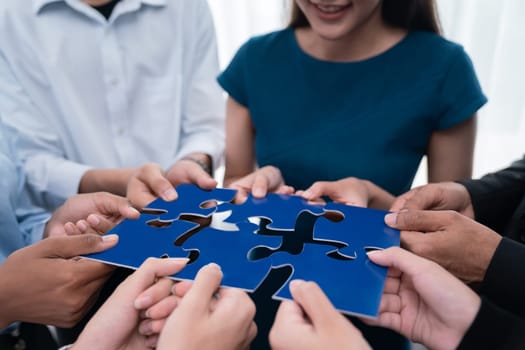 Diverse corporate officer workers collaborate in office, connecting puzzle pieces to represent partnership and teamwork. Unity and synergy in business concept by merging jigsaw puzzle. Concord