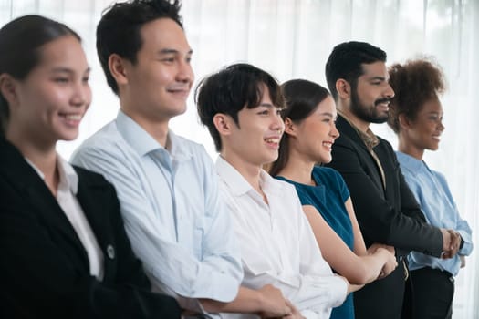 Happy and smiling multiracial office worker hold hand in a line, promoting synergy and collaboration for business success. Diverse professional office worker bond at modern workplace. Concord