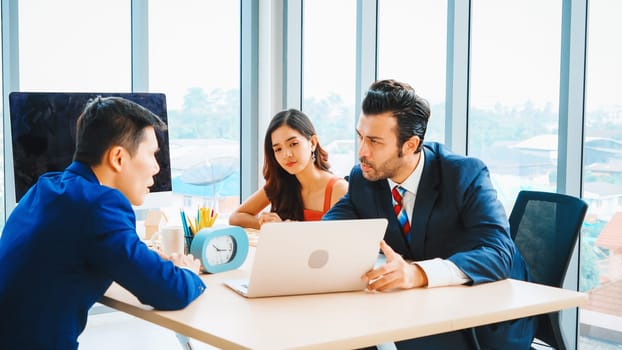 Smart businessman and businesswoman talking discussion in group meeting at office table in a modern office interior. Business collaboration strategic planning and brainstorming of coworkers. Jivy