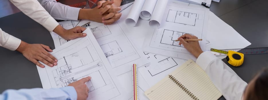 Engineer partner drawing and working on blueprint design together on office table for architectural building construction project. Architect drafting interior blueprint layout. Insight