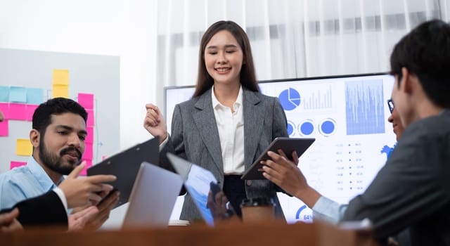 Young asian businesswoman presenting data analysis dashboard on TV screen in modern meeting. Business presentation with group of business people in conference room. Concord