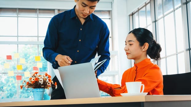 Two business people talk project strategy at office meeting room. Businessman discuss project planning with colleague at modern workplace while having conversation and advice on financial report. Jivy