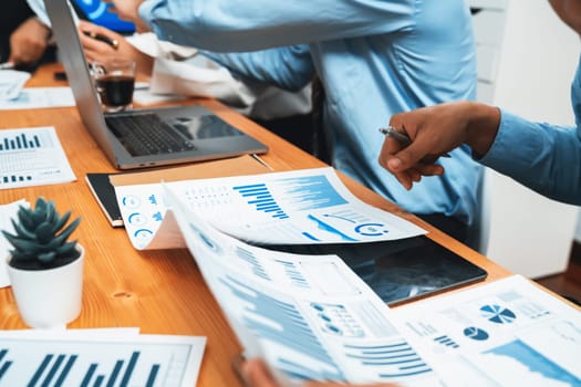 Diverse group of business analyst team analyzing financial data report paper on office table. Chart and graph dashboard by business intelligence analysis for strategic marketing planning Habiliment