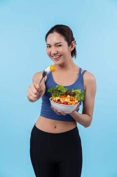 Young sporty Asian woman in sportswear holding salad bowl fill with vibrant of fruit and vegetable. Natural youthful and fit body lifestyle with balance nutrition on isolated background. Vigorous